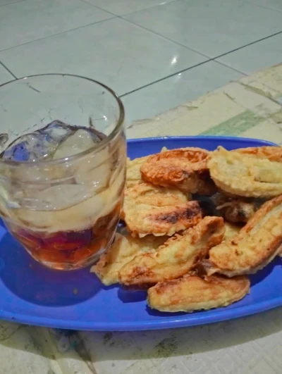 Secangkir es teh, sepiring pisang goreng